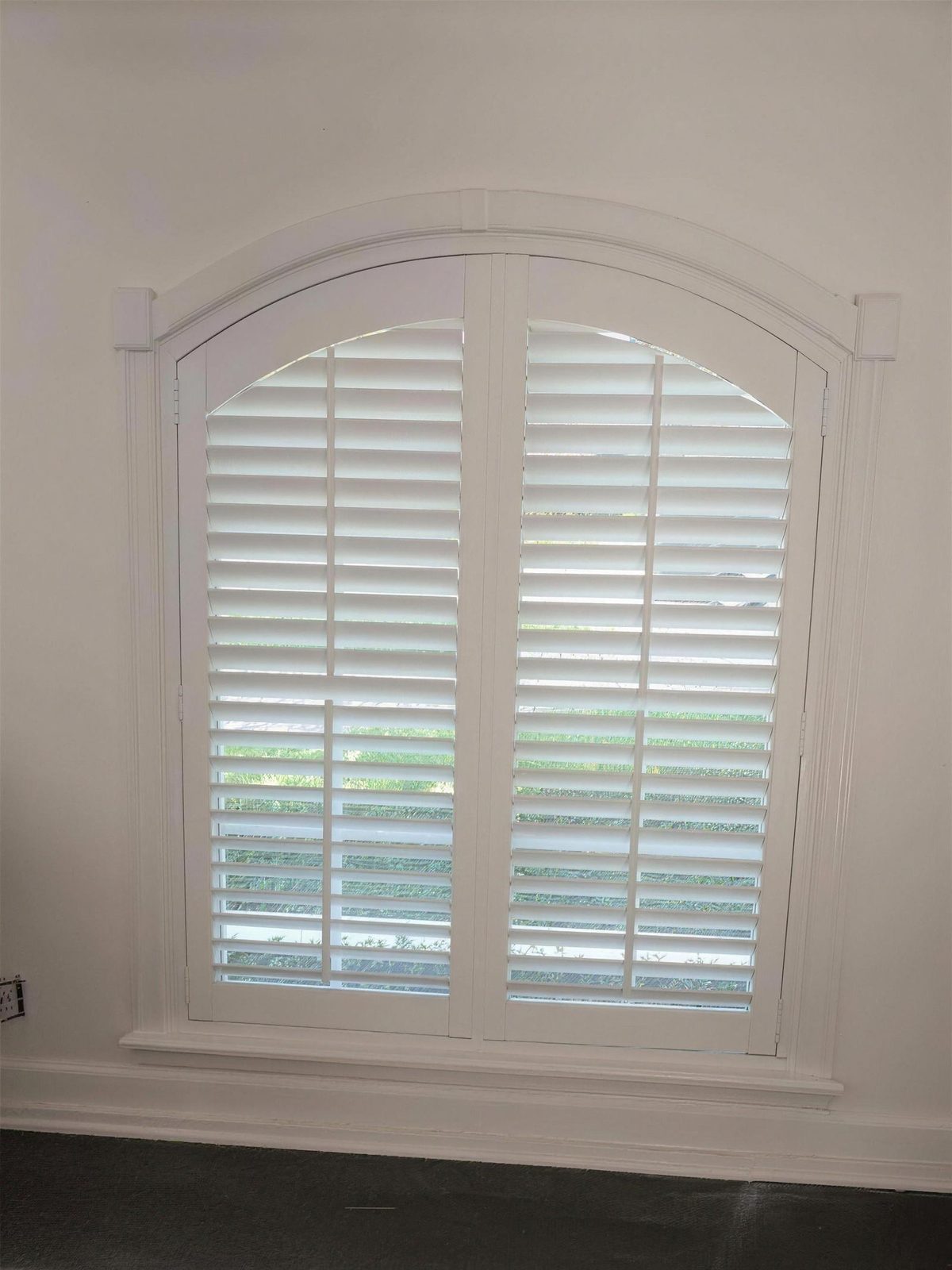 Tall arched window with a custom-built curved shutter