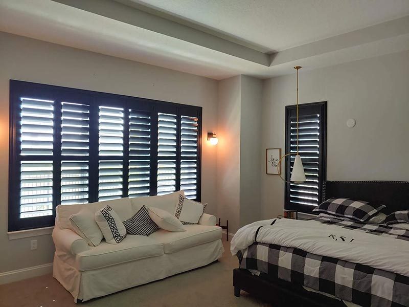 Black plantation shutters in a bedroom suite with buffalo check bedding