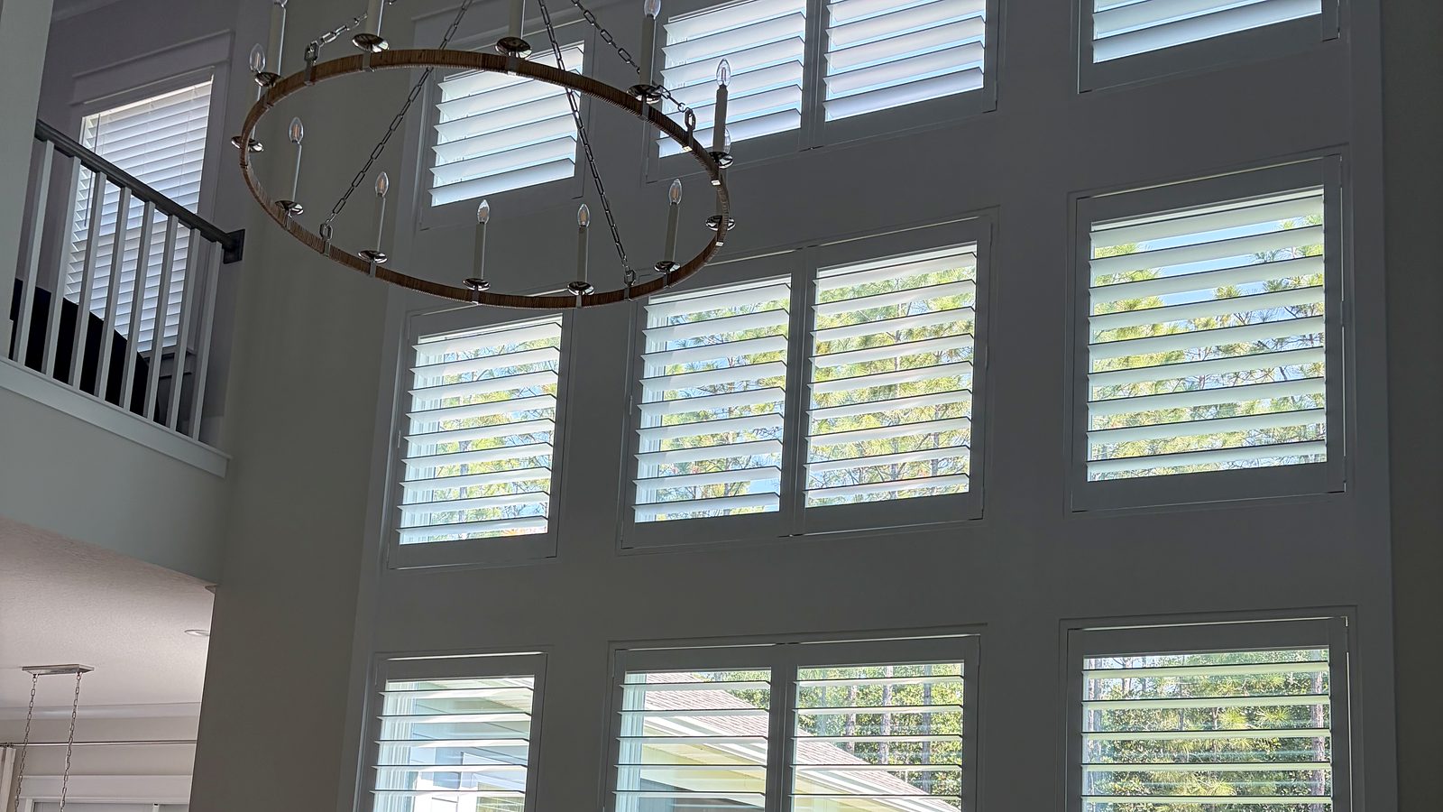 Two-story wall of custom white plantation shutters in a Jacksonville home